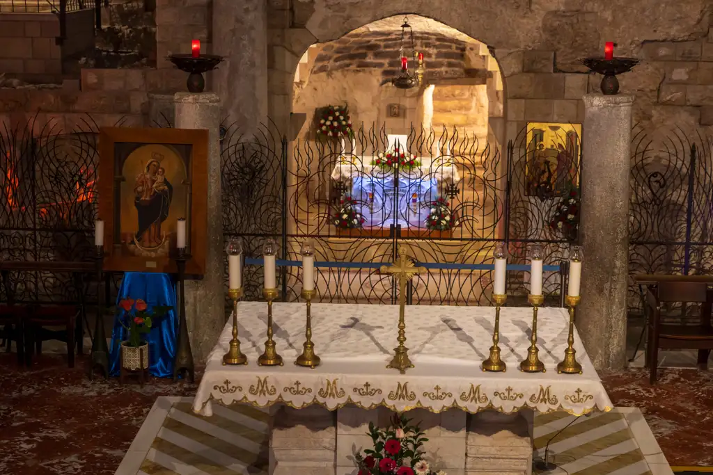The Grotto of the Annunciation behind its wrought-iron grille, with icons and lit altar candles.